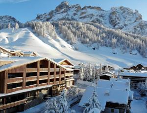 サン・カッシアーノにあるHotel Diamantの雪に覆われた山々を背景にしたリゾート