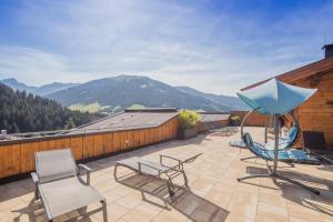 un patio con sillas y una sombrilla azul en el techo en Hotel Alphof Alpbach, en Alpbach