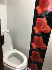 a bathroom with a toilet with red flowers on the wall at Hang Ho Hostel in Hong Kong