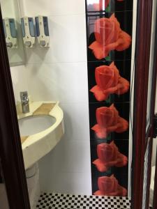 a bathroom with a sink and red flowers on the wall at Hang Ho Hostel in Hong Kong