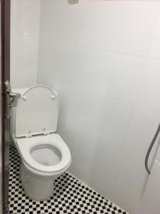 a white toilet in a bathroom with a checkered floor at Hang Ho Hostel in Hong Kong