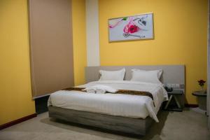 um quarto com uma grande cama branca com paredes amarelas em Green Rose Hotel em Batam Center