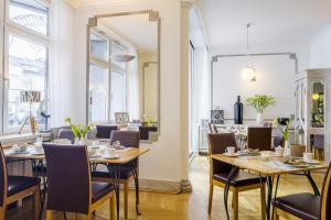 a dining room with tables and chairs and a mirror at Hotel Am Helmwartsturm in Andernach