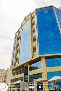 un edificio alto con ventanas de cristal azul y sombrillas en Bristol Hotel Salalah, en Salalah