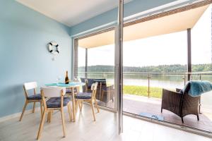 een eetkamer met een tafel en stoelen en een groot raam bij Apartamenty Mazurskie Klimaty (Cud Natury) in Tomaszkowo