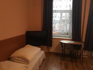 a bedroom with a bed and a table and a television at Penzion T&T in Cheb