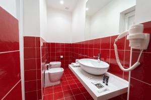 La salle de bains est pourvue de carrelage rouge, d'un lavabo et de toilettes. dans l'établissement HG Boutique Toledo, Napoli Centro, by ClaPa Group, à Naples