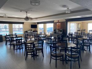 uma sala de jantar com mesas, cadeiras e janelas em Galveston Beach Hotel em Galveston