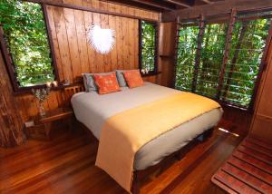 een slaapkamer met een bed in een kamer met ramen bij The Canopy Rainforest Treehouses & Wildlife Sanctuary in Tarzali