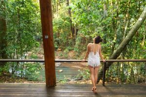 een vrouw die over een houten brug in een bos loopt bij The Canopy Rainforest Treehouses & Wildlife Sanctuary in Tarzali