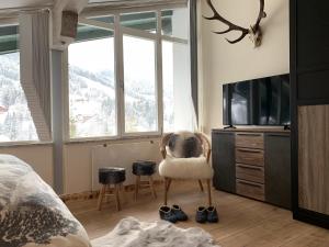 een slaapkamer met een bed en een stoel en een tv bij Apartment Lausbuam in Mühlbach am Hochkönig