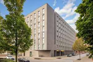 un grand bâtiment dans une rue avec des voitures garées à l'extérieur dans l'établissement Super 8 by Wyndham Hamburg Mitte, à Hambourg