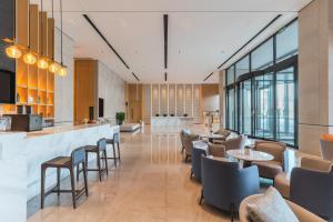 um restaurante com mesas e cadeiras e um bar em Hyatt Place Changchun Jingyue em Changchun