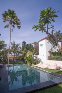 una piscina en un patio con palmeras en The Palms Canggu, en Canggu