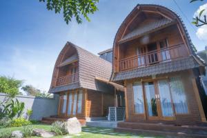 una casa de madera con techo de gambrel en The Palms Canggu, en Canggu