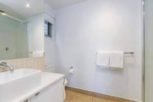 een witte badkamer met een wastafel en een douche bij The Victoria Apartments in Port Fairy