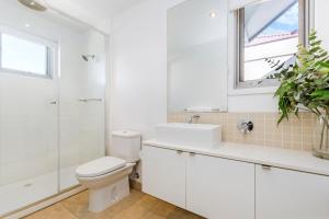 een witte badkamer met een toilet en een wastafel bij The Victoria Apartments in Port Fairy