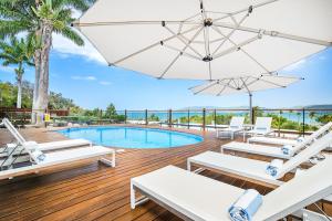 um deque com cadeiras, uma piscina e um guarda-sol em Freedom Shores Resort Airlie Beach em Airlie Beach