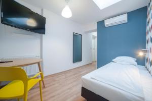 a bedroom with a bed and a desk and a yellow chair at Atlantis Hostel in Kraków