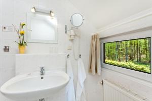 baño blanco con lavabo y ventana en Restaurant & Hotel Baumhaus Hagen, en Sassnitz