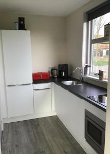 a kitchen with white cabinets and a sink and a window at Vissers Huus Hollum Ameland in Hollum