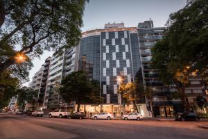 un edificio alto con macchine parcheggiate di fronte di Vivaldi Hotel Loft Punta Carretas a Montevideo