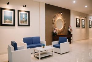 - une salle d'attente avec des chaises bleues et un miroir dans l'établissement Merlin Hotel, à Maumere