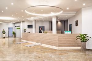 a lobby with a woman standing at a reception desk at H+ Hotel Stuttgart Herrenberg in Herrenberg