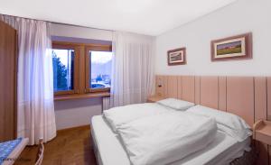 una camera con un letto bianco e una finestra di Hotel Terme a Bormio