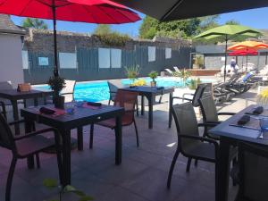 a patio with tables and umbrellas and a swimming pool at Le Thalassa Hôtel & Spa in Camaret-sur-Mer