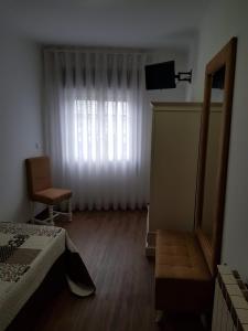 1 dormitorio con cama, ventana y silla en Residencial Solar da Estação, en Barcelos