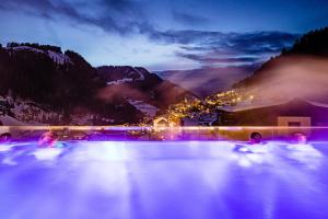 una vasca idromassaggio con luci in montagna di notte di Hotel Touring Dolomites a Santa Cristina in Val Gardena