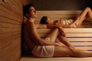 un uomo e una donna seduti in una sauna di Hotel Arnolfo & Aqua Laetitia Spa & Beauty a Montecatini Terme