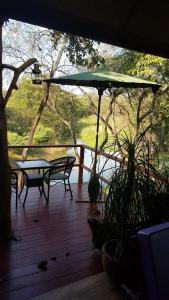 una terraza con 2 bancos, una mesa y una sombrilla en Riverside, en Ban Cho Lae