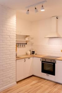 a kitchen with white cabinets and a white brick wall at Eco apartament Nałęczów in Nałęczów