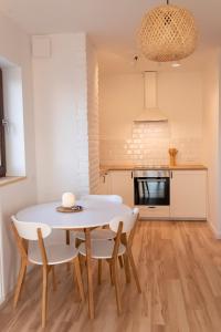 a kitchen and dining room with a white table and chairs at Eco apartament Nałęczów in Nałęczów