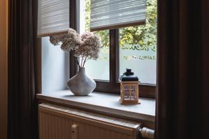 a window sill with a vase with flowers and a candle at athome IHR Apartment in Chemnitz