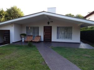 uma pequena casa branca com duas cadeiras no quintal em Casa Simona Villa General Belgrano em Villa General Belgrano