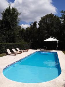 uma piscina com cadeiras e um guarda-sol em Casa Simona Villa General Belgrano em Villa General Belgrano