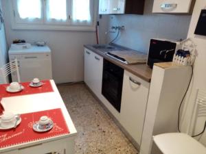 a small kitchen with a red table and a white refrigerator at L'Angolo Di San Pietro in Rome