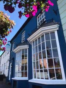 een blauw gebouw met witte ramen en roze bloemen bij The Blue Mantle in Wellington