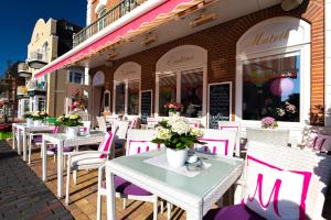 una fila di tavoli e sedie di fronte a un ristorante di La Maison M a Westerland