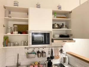 een keuken met witte kasten en een magnetron boven een wastafel bij Repubblica One Room Apartment in Milaan