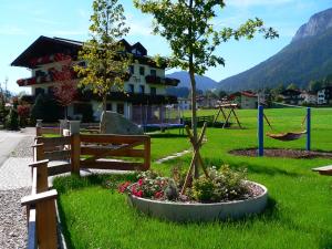 um parque com um banco, uma árvore e um baloiço em Ferienhotel Tyrol Söll am Wilden Kaiser em Söll