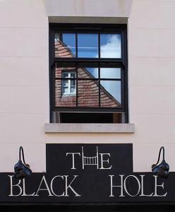 un panneau noir sur un bâtiment avec fenêtre dans l'établissement The Black Hole, à Winchester