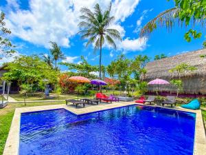 una piscina con sedie e ombrelloni di fronte a una casa di Namaste Bungalows a Nusa Penida