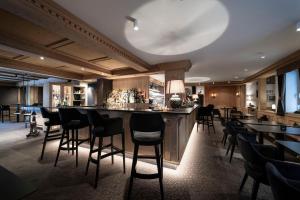 a bar in a restaurant with black bar stools at Hotel Acadia - Adults Mountain Home in Selva di Val Gardena