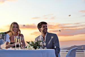 un hombre y una mujer sentados en una mesa con copas de vino en Thermes Luxury Villas And Spa, en Megalokori