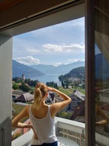 een vrouw die op een balkon staat en uit een raam kijkt bij la belle vue Boutique Hotel & Café in Spiez