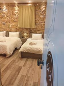 a bedroom with two beds and a stone wall at CityZen Rooms Chios in Chios